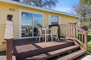 A wooden deck with a table and chairs, a wooden staircase, and a sliding glass door.
