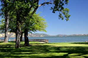 A park with a wooden bridge over a lake, surrounded by trees and a distant mountain range. - Skylark Shores Resort (Lakeport)