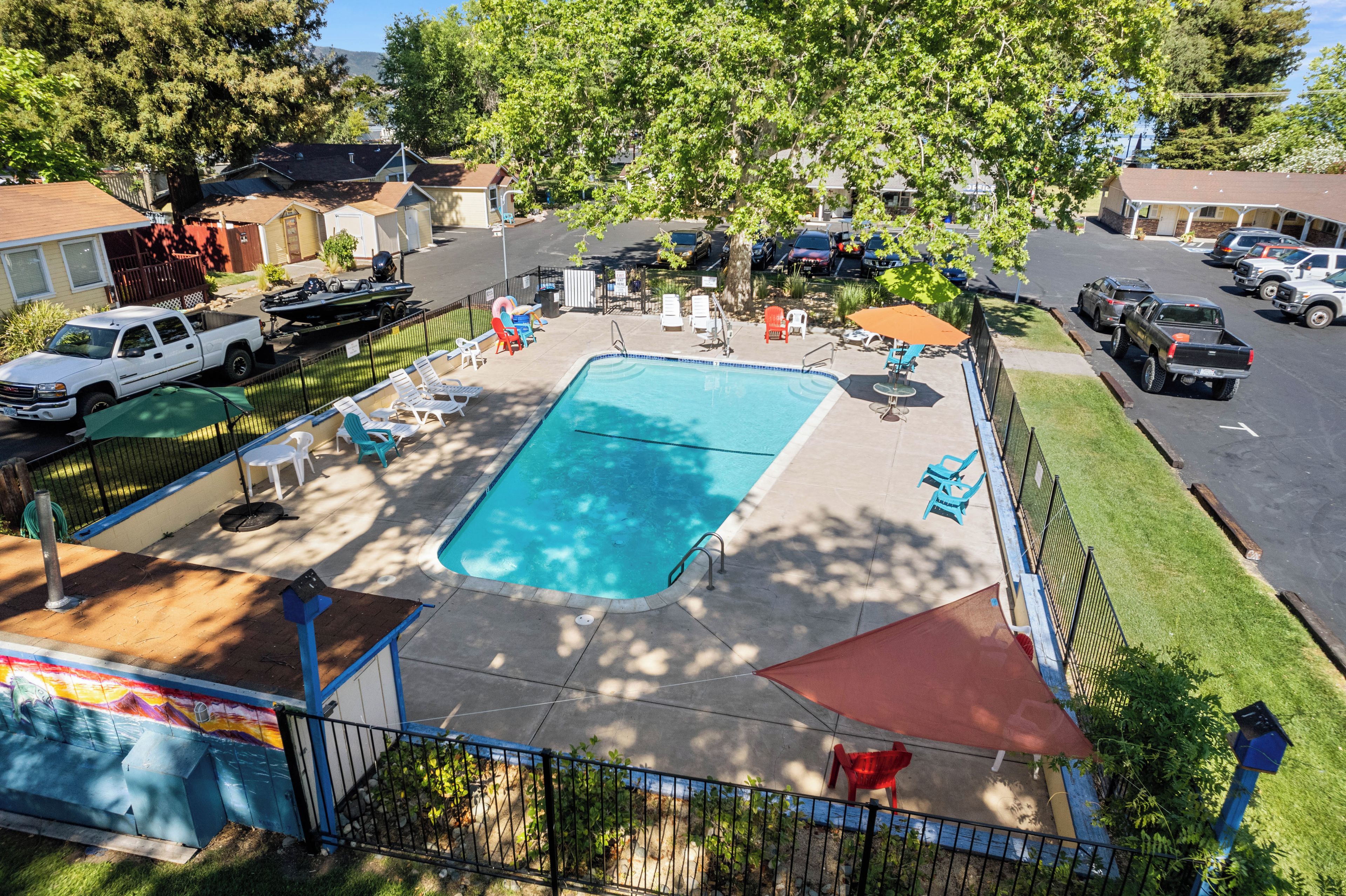 A rectangular pool with a surrounding deck, lounge chairs, and a covered seating area.