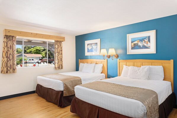 A hotel room with two beds, a window with curtains, and two framed pictures on the wall. - Skylark Shores Resort (Lakeport)