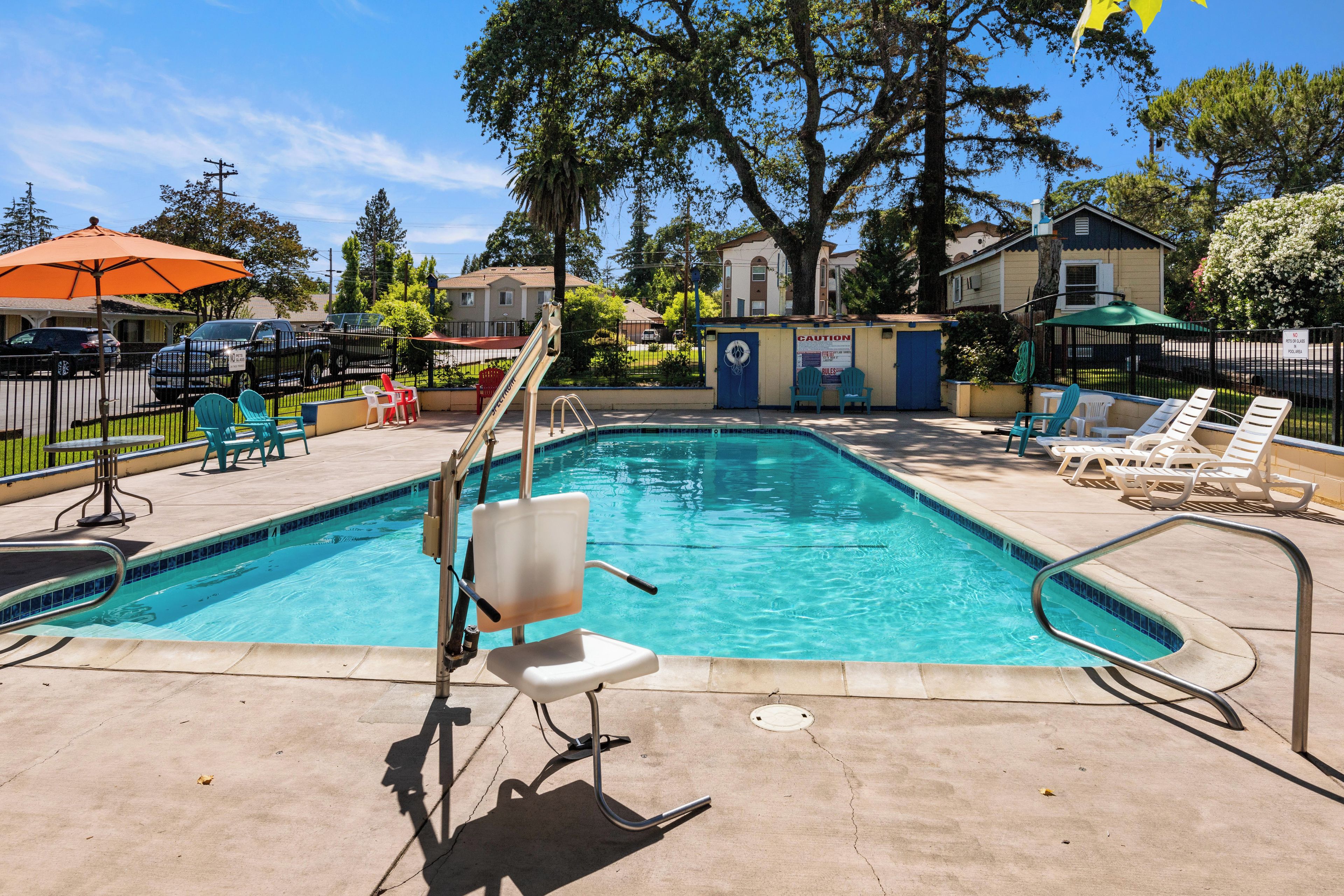 A swimming pool with a slide, lounge chairs, and a caution sign.