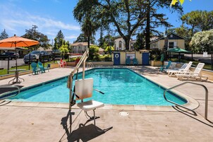 Una piscina con tobogán, sillas de descanso y un cartel de precaución.