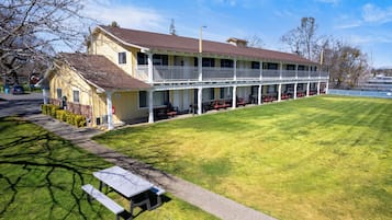 A two-story motel with a covered patio area, outdoor seating, and a well-maintained lawn.