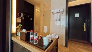 A hotel room with a wooden reception desk, a mirror, a towel rack, and a door. - Xianheng Hotel (Shaoxing)
