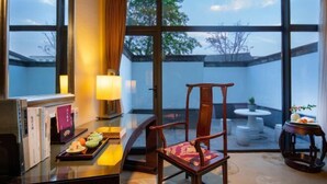 A room with a wooden chair, a table with a tray of food, and a view through large windows. - Xianheng Hotel (Shaoxing)