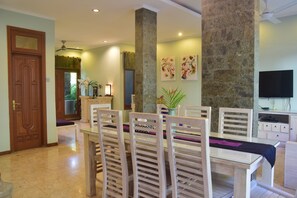 A dining area with a table, chairs, and a stone pillar. - Villa Putu Mira By Maha Bali (Kuta)