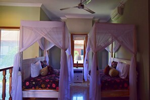 A room with two beds, each with a canopy, a bedside table, and a lamp. - Villa Putu Mira By Maha Bali (Kuta)
