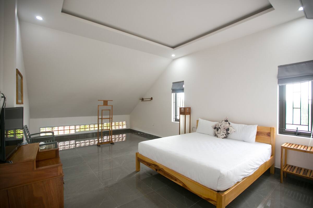 Een slaapkamer met een houten bed, een bureau en een televisie.