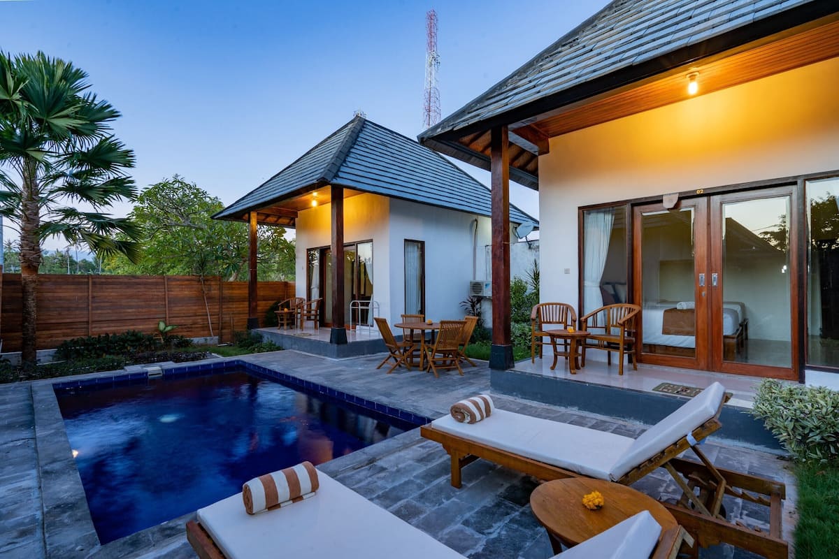 Una casa moderna con piscina, mobiliario exterior y un amplio ventanal corredero.