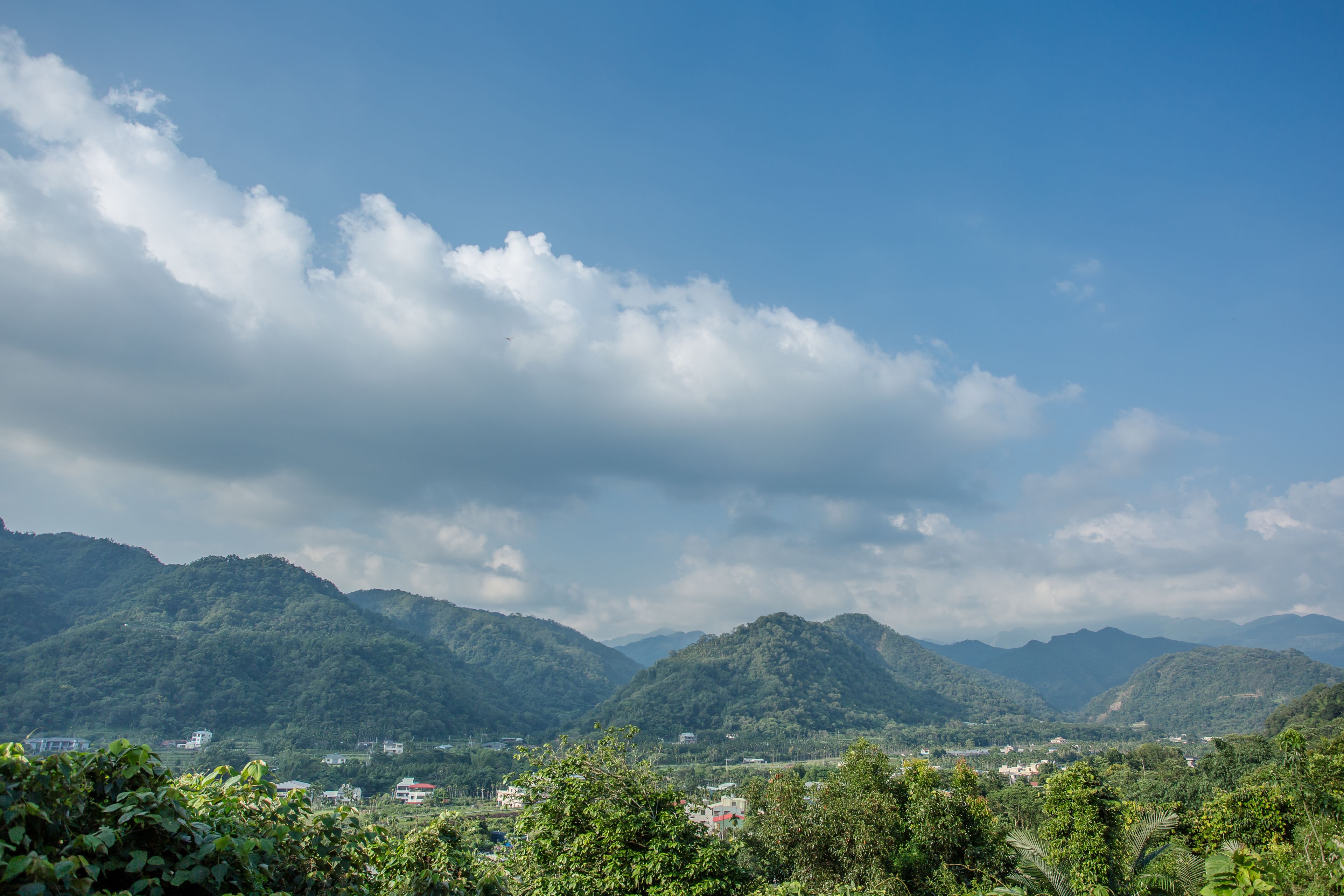 A mountainous landscape with lush greenery and scattered buildings.