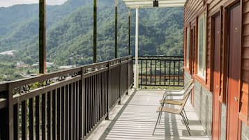 Enjoy breathtaking views of the surrounding mountains from this balcony, featuring two comfortable chairs and an outdoor space.
