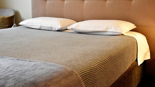 A bed with a tufted headboard, two pillows, and a textured grey bedspread. - Ribeira Oporto Apartment (New) (Porto)