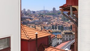 A cityscape with a prominent tower, terracotta-roofed buildings, and a river. - Ribeira Oporto Apartment (New) (Porto)