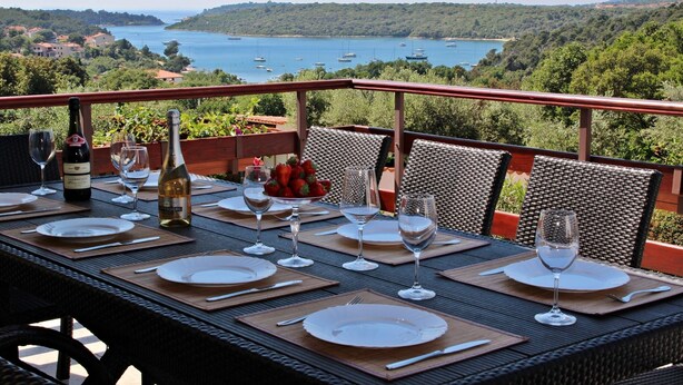 A table set for dining with a view of a bay and boats.