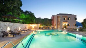 Une piscine avec des chaises longues, un mur en pierre et un bâtiment doté de nombreuses fenêtres.