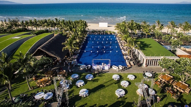 Vista aerea di un resort con una grande piscina, spiaggia e palme.