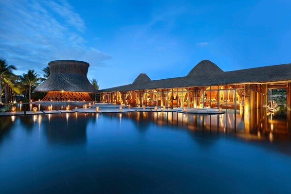 A resort with a large swimming pool, a distinctive conical structure, and a thatched-roof building. - Luxury Pool Villa Resort (Da Nang)