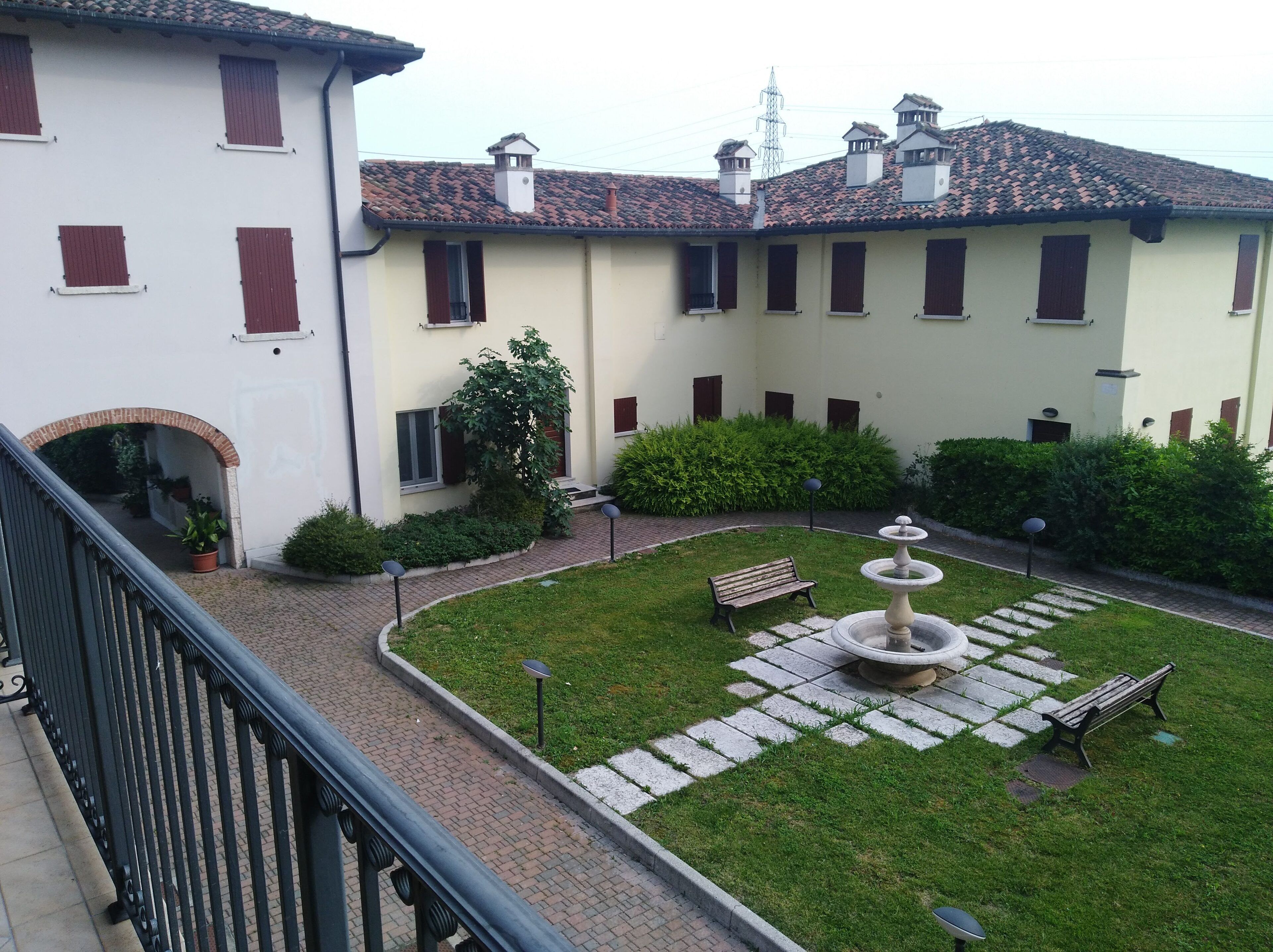 Un patio con una fuente, bancos y un pequeño jardín.