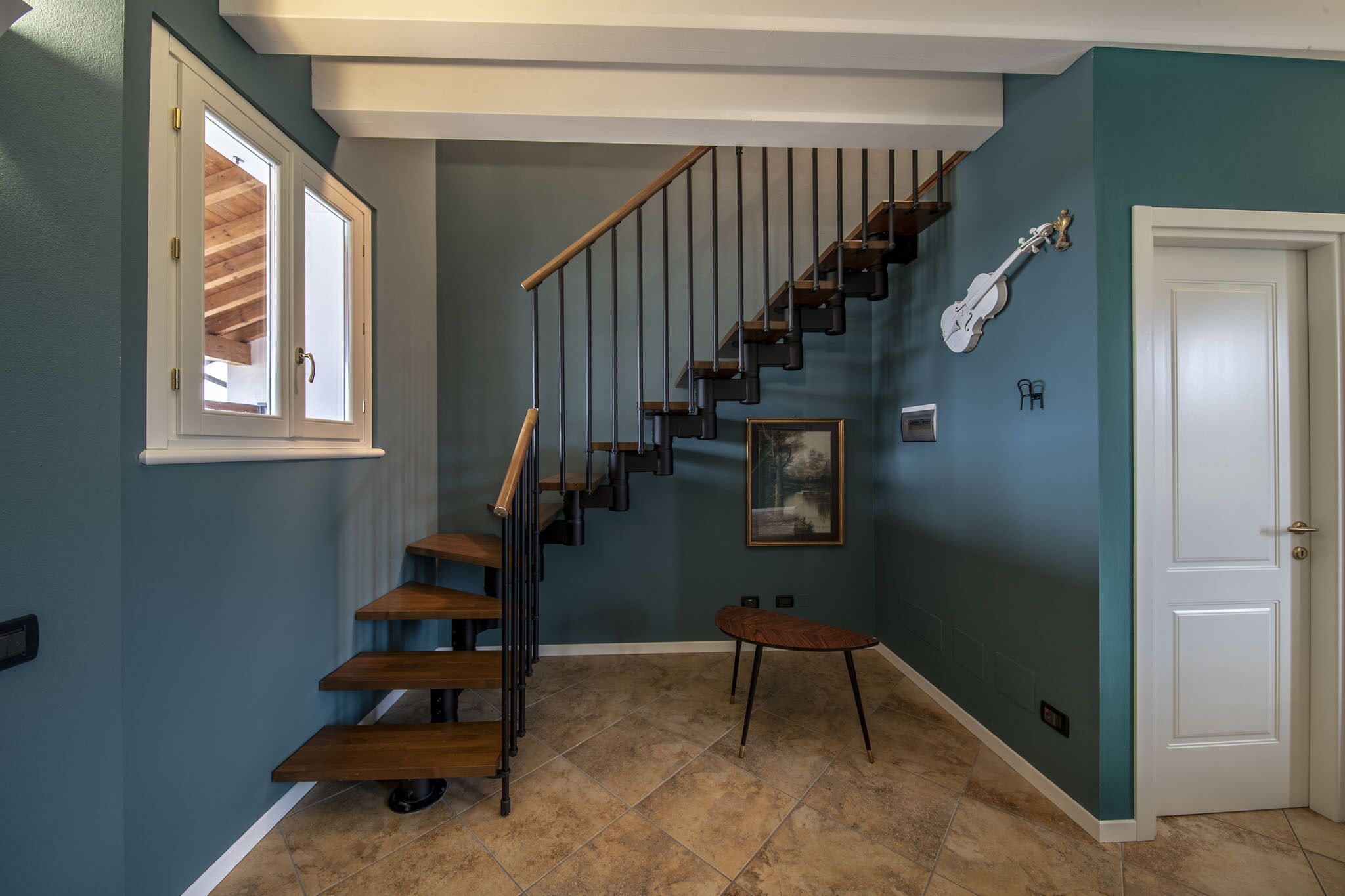 A staircase with wooden steps and a metal railing, leading to a second floor.