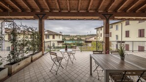 A covered outdoor patio with a wooden ceiling, tiled floor, and a table with chairs. - "DESIGNcontrodesign  (desenzano)