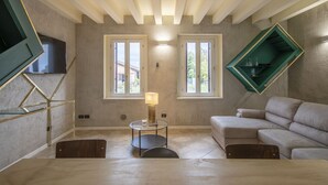 A modern living room with a sofa, a glass table with a lamp, and a TV mounted on the wall. - "DESIGNcontrodesign  (desenzano)