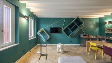 A modern kitchen with teal walls, a wooden dining table, and a built-in microwave.