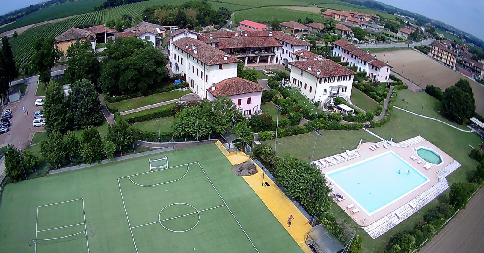 Eine Vogelperspektive zeigt eine Wohngegend mit Häusern, einem Fußballfeld und einem Schwimmbad.