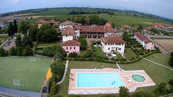 An aerial view of a residential area with houses, a tennis court, and a swimming pool.