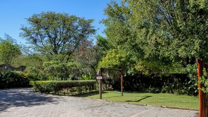Un camino de entrada pavimentado que conduce a una entrada con portón y un letrero que dice 'PARKING'.