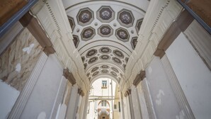 Un couloir doté d’un plafond décoratif orné de motifs géométriques et d’une fenêtre centrale.