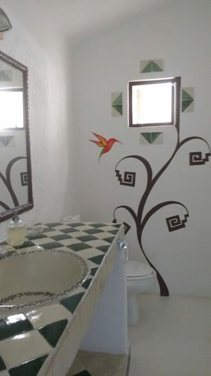 A bathroom with a checkered floor, a mirror, a toilet, and decorative wall stickers.
