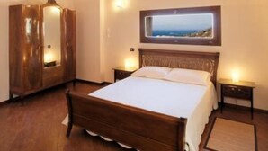 A bedroom with a wooden bed, a wardrobe, and a framed picture on the wall. - MAGNIFICENT, WARM APARTMENT IN THE HEART OF A TYPICAL SICILIAN VILLAGE! (Torretta)