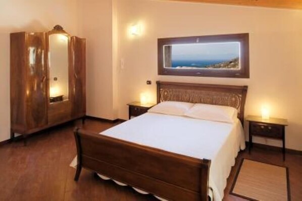 Een slaapkamer met een houten bed, een kledingkast en een ingelijst kunstwerk aan de muur.