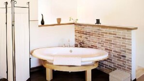 A bathroom with a freestanding bathtub, a radiator, a brick wall, and a shelf with decorative items. - MAGNIFICENT, WARM APARTMENT IN THE HEART OF A TYPICAL SICILIAN VILLAGE! (Torretta)
