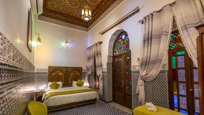 Una habitación tradicional marroquí con una cama, una mesita y una silla.