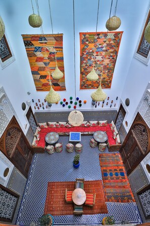 A traditional Moroccan interior with geometric tile patterns, hanging woven lamps, and colorful rugs.