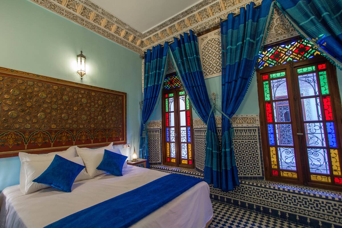 A room with a bed, blue curtains, and patterned walls.