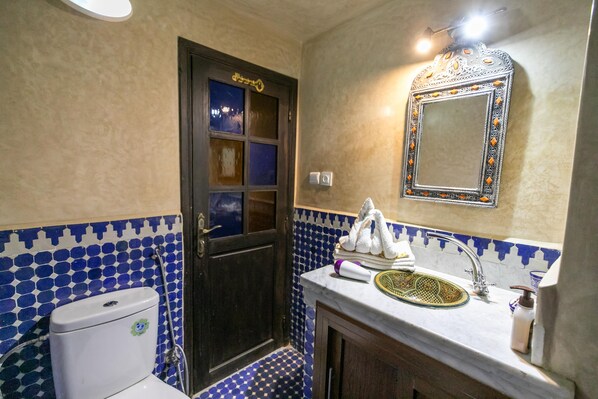 A bathroom with a toilet, sink, and mirror.