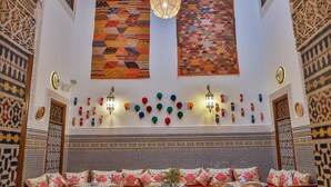 Una habitación con diseños complejos en las paredes, una alfombra grande y una zona de estar con cojines y una mesa.