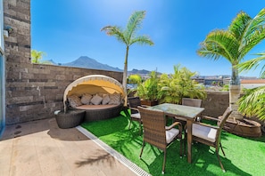A patio with a round seating area, a table with chairs, and potted plants. - Spacious 5BR Villa in Costa Adeje with Private Pool (Costa Adeje)