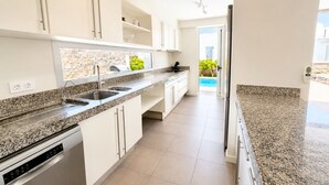 Eine moderne Küche mit Granit Arbeitsplatten, Edelstahlgeräten und Blick auf einen Swimmingpool.