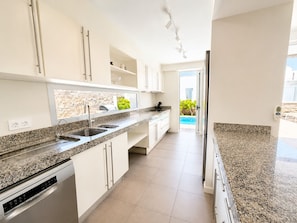 A modern kitchen with granite countertops, stainless steel appliances, and a view of a swimming pool.