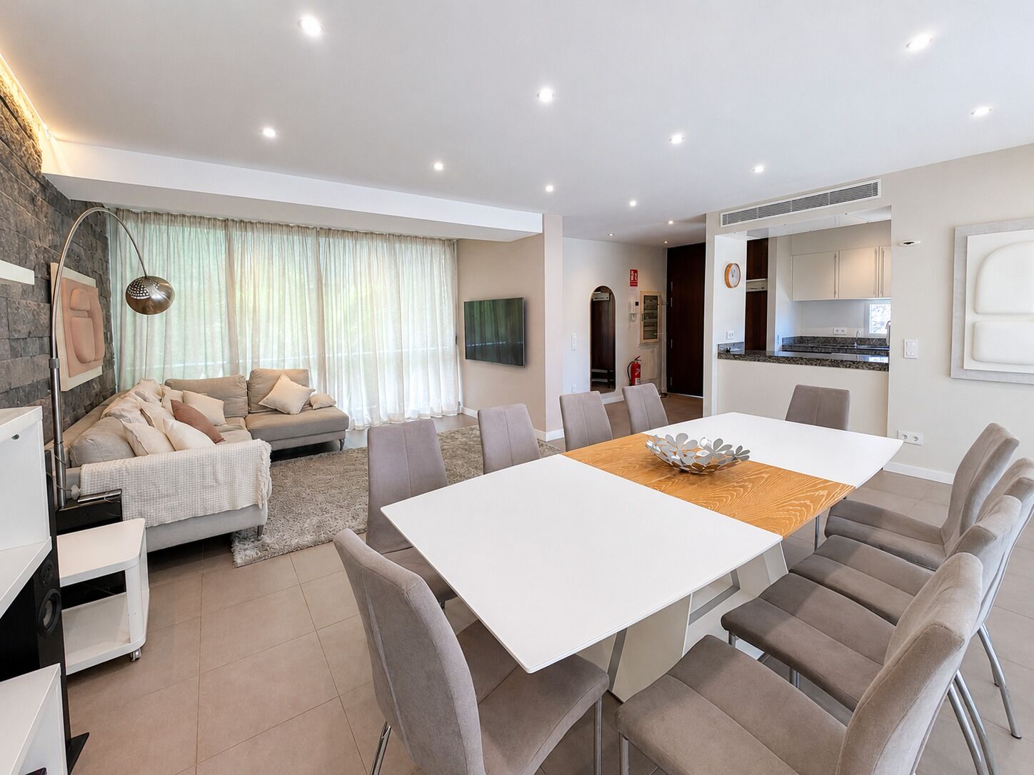 Un salon moderne comprenant un canapé, une table à manger et des chaises, un coin cuisine et une cheminée.