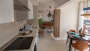 A modern kitchen with a dining area, featuring a central island, a built-in oven, and a dining table with chairs. - Villa Guájara  (Playa Blanca)