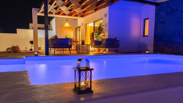 An outdoor swimming pool area with a wooden pergola, seating, and a lantern. - Villa Guájara  (Playa Blanca)