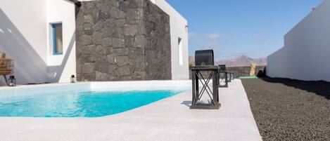 Ein moderner Poolbereich mit einer Steinmauer und weißen Gebäuden im Hintergrund.