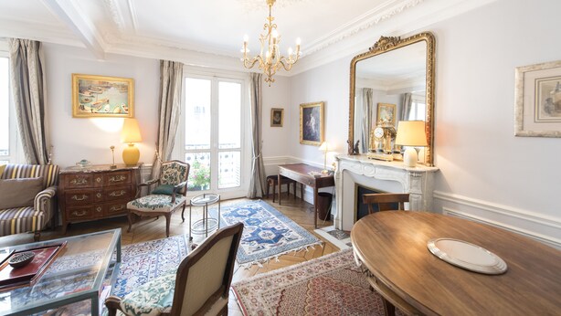 A well-furnished room with a chandelier, a large mirror, a fireplace, and a dining table. - Saint-Germain des Prés Allure, by Veeve (Paris)