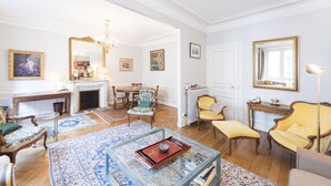 A spacious living room with a fireplace, comfortable seating, and a large mirror. - Saint-Germain des Prés Allure, by Veeve (Paris)