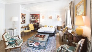 A spacious living room with a large bed, a coffee table, and a bookshelf. - Saint-Germain des Prés Allure, by Veeve (Paris)