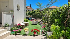 A garden with potted plants, a bench, and a table. - Deluxe Apartments Goya (Zadar)